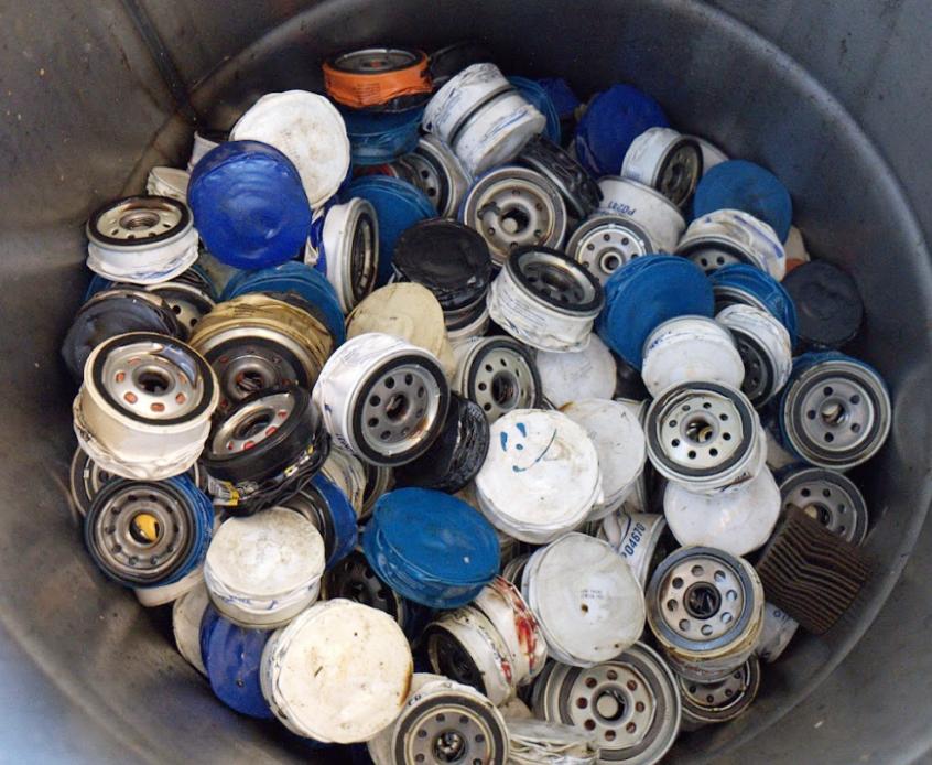 Used oil filters collected in a metal drum for disposal or recycling.